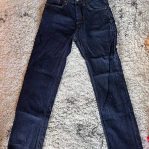 Mörkblå jeansbyxor från 157 Seattle - Säljer ett par mörkblå jeansbyxor från Lager 157 modell Seattle. Klassisk femficksmodell med raka ben och normal passform. Jeansen har gylf med dragkedja och knapp, samt tydliga sömmar i kontrastfärg.