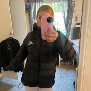 Svart pufferjacka från Adidas - Säljer en svart pufferjacka från Adidas som e perfekt under vintern.