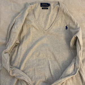 Ljusgrå v-ringad tröja från Polo Ralph Lauren - En jättefin grå v-ringad tröja från Polo ralph lauren. I st S och sitter fint på kroppen. Använd ca 3 gånger men är i bra skick. OBS tvättar kläderna innan dem skickas❤️