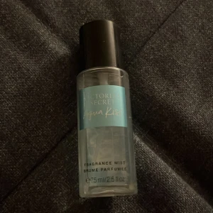 Victoria's Secret Aqua Kiss Fragrance Mist - Fräsch body mist från Victoria's Secret i doften Aqua Kiss. Flaskan är genomskinlig med blå etikett och svart lock. Innehåller 75 ml och är perfekt att ta med i väskan för en uppfriskande doft när som helst.