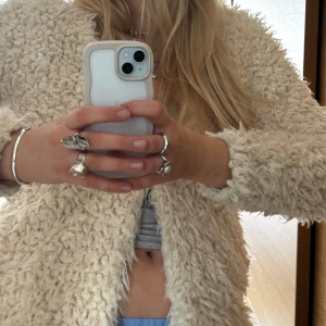 Beige/vit teddyjacka - Säljer en fluffig beige teddyjacka med lång ärm. Jackan har en mysig och trendig look, perfekt för att hålla värmen under kyliga dagar. Passar dig som gillar en avslappnad och cool stil.             Använt skick o lite ”smutsig” på vissa ställen men annars inga problem💗