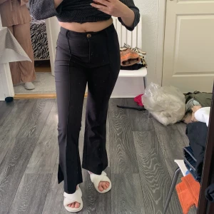 Svarta bootcut-byxor från SHEIN - Svarta bootcut-byxor från SHEIN med hög midja och klassisk knapp- och dragkedjestängning. Byxorna har en figurnära passform upptill och utsvängda ben nertill. Perfekta för en trendig och stilren look.