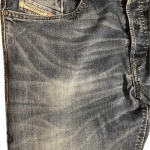 Blå Diesel jeansbyxor med slitningar - Blå jeans från Diesel med snygga slitningar och tvättade detaljer. 