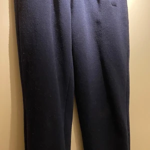 Mörkblå mjukisbyxor med resårmidja - Mörkblå mjukisbyxor med resår i midjan och sidofickor. Byxorna har en rak passform och är gjorda i ett mjukt, stickat material som känns skönt mot huden. Perfekta för en avslappnad stil.