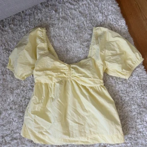 Gul topp  - Söt ljusgul blus med puffiga korta ärmar och rynkade detaljer vid bysten. Jättesöt!