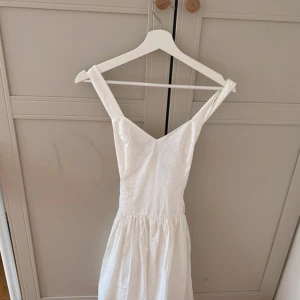 Vit klänning med knyt i ryggen - Superfin vit klänning med v-ringning och breda axelband. Knytning i ryggen ger en snygg detalj och passformen är normal. Perfekt för sommarens alla tillfällen! Den är i storlek S men eftersom att den gör att knyta i ryggen så passar den även som en Xs!