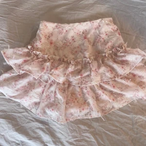 Blommig volangkjol  - Supersöt kjol med volanger och blommigt mönster i ljusrosa och vitt. Helt oanvänd💕