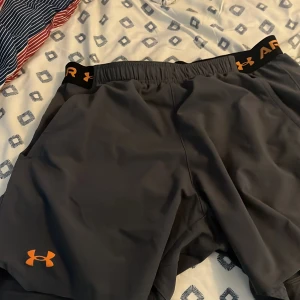 Under armor shorts  - Hejsan, säljer ett par under armour shorts i storlek L med grå färg och orangea detaljer
