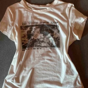 Vit t-shirt med tryck 'Be Your Own Sun' - Vit t-shirt med coolt svartvitt tryck och texten 'Be Your Own Sun' på bröstet. Klassisk rund hals och korta ärmar. Perfekt för dig som gillar en avslappnad och trendig stil.