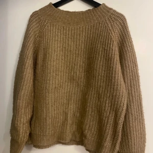 Beige stickad tröja  - Mysig beige stickad tröja med grov struktur och bred ribbad kant vid halsen. Tröjan har lång ärm och en avslappnad passform. Gott skick! 