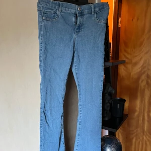 Ljusblå bootcut jeans från Kids Only - Snygga ljusblå jeans från Kids Only i storlek 152. Modellen har bootcut-ben, klassiska fem fickor och dragkedja med metallhake. Jeansen är gjorda i mjukt denimtyg och har en normal passform som sitter skönt hela dagen. En lite ovanligare knapp sol fungerar ungefär som en krok. Justerbar midja med knappar och resorband. 60 cm midjemått, 92cm top till tå