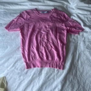 Rosa kortärmad tröja från Zara - Säljer en söt rosa tröja från Zara med korta ärmar och rund hals. Tröjan är i mjuk bomullsmix och har en slim passform som sitter snyggt på kroppen. Perfekt till vår och sommar för en fräsch look. Igga att jag har ett linne under