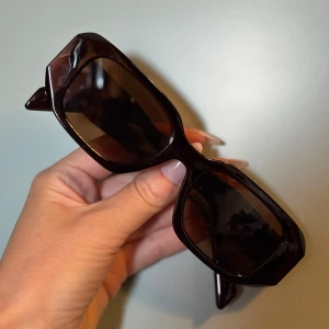 Solglasögon Prada PR 17Ws - Snygga mörkbruna solglasögon från Prada. Bågarna är i kraftig plast och har märkets logga på sidorna i silvrig färg. Perfekt accessoar för en trendig look. Bredd 49 mm. UV 400. Använda någon enstaka gång men passade inte riktigt mitt ansikte. Välkommen med frågor eller bud 🌸