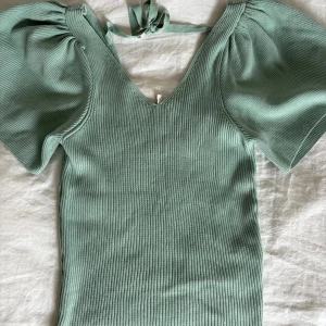 Ribbad grön topp med puffärm och knyt - Superfin ljusgrön ribbad topp med v-ringning, puffiga korta ärmar och knytband i nacken. 