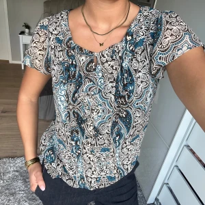 Mönstrad blus i blått och svart - Säljer en snygg blus med korta ärmar och ett detaljerat paisleymönster i blått, svart och vitt. Perfekt till sommaren, hör av dig vid frågor 💛💛