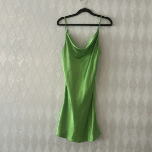 Grön satinklänning från Gina Tricot - Snygg grön kort satinklänning från Gina Tricot med tunna ställbara axelband och draperad urringning. Klänningen har en slimmad passform och skimrande yta som ger en trendig look. Perfekt för dig som vill sticka ut med färg och stil. Passar mig som har S också 