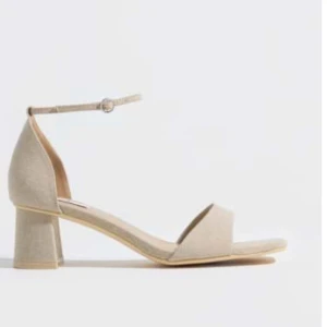 Klackskor från Nelly - Stilrena beige sandaler från Nelly med fyrkantig tå, låg blockklack och smal rem runt ankeln. Skorna är i textilmaterial och har en öppen design som passar perfekt till varmare dagar. Snygga att matcha med både jeans och klänning. Helt nya aldrig använda och priset går att diskutera vid ett snabbt köp. Nypris 399kr