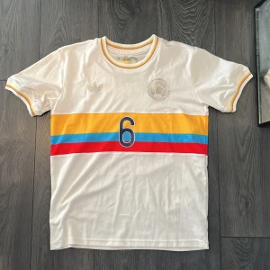 Colombia 100-års jubileumsfotbollströja Adidas - Exklusiv Colombia fotbollströja från Adidas, 100-årsjubileum 1924-2024. Vit ”cream” bas med gula, blå och röda horisontella ränder som visar Colombias flagga, nummer 6 och ”Danskungen” Richard Rios på ryggen. Öppen till bud!🤗😊