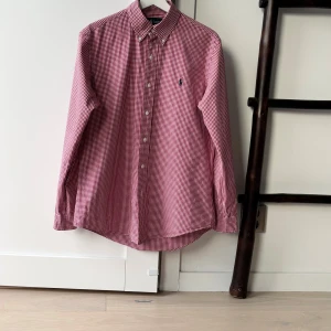 Ralph Lauren skjorta M herr - vit röd rutig, custom fit👔 - Klassisk Ralph Lauren-skjorta i modellen Custom Fit, herrstorlek M. Vit med röda rutor, 100 % bomull. Sparsamt använd och i jättebra skick – inga fläckar eller skador. Perfekt för en stilren, preppy look.  📦 Skickas inom en dag! 💬 Hör av dig vid frågor eller prisförslag?