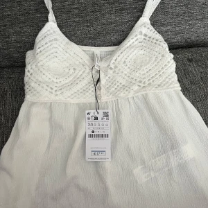 Vit topp från Stradivarius - Supersöt topp från Stradivarius med virkade detaljer upptill och smala axelband. Överdelen har knappar framtill och ett snyggt mönster, Perfekt för varma dagar och sommarvibbar!