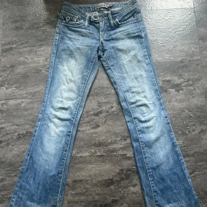 Blå bootcut jeans från Sjeans - Snygga blå bootcut jeans från MNGjeans med coola fickor och låg midja, midjemåttet är ca 34 cm. De har tyvärr gått sönder lite vid midjan vilket man ser på bild 4, men inget som man tänker på eller som inte kan lagas. De har även lite slitningar längst ner på benet (bild 5). Kom privat vid fler frågor.💕