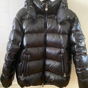  MonclerJacka ”Maya” storlek 3 Large Nyskick!! - Säljer en svart jacka från Moncler ”Maya” storlek 3 med huva och dragkedja framtill. Jackan har två stora fickor med dragkedja och en extra ficka med Moncler-logga på ärmen. Perfekt för kalla dagar och riktigt snygg streetstil. Dragkedjan i innerfickan fattas därav priset, använd bara en gång. Nyskick!! Mvh