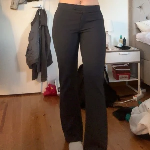 Svarta bootcut kostymbyxor - Säljer ett par svarta kostymbyxor med bootcut-snitt och hög midja. Byxorna har en stilren look och är gjorda i ett mjukt material som sitter snyggt över höfterna och faller rakt ner. Perfekta om du vill ha en clean och trendig vibe.