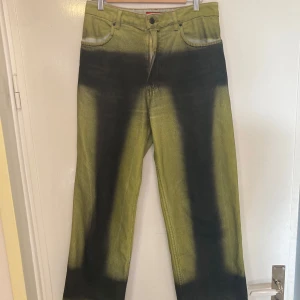 Grön-svarta jeansbyxor från Eckhaus Latta - Unika grön-svarta jeansbyxor från Eckhaus Latta med en svart o grön acid wash. Byxorna har a straight leg fit och är tillverkade i USA. 