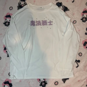 Vit långärmad tröja med lila tryck - Säljer en vit långärmad tröja med ett lila tryck på framsidan. Tröjan har en avslappnad passform och är perfekt för en casual look. Den är gjord i ett mjukt material som känns skönt mot huden. Från märket Majoretty