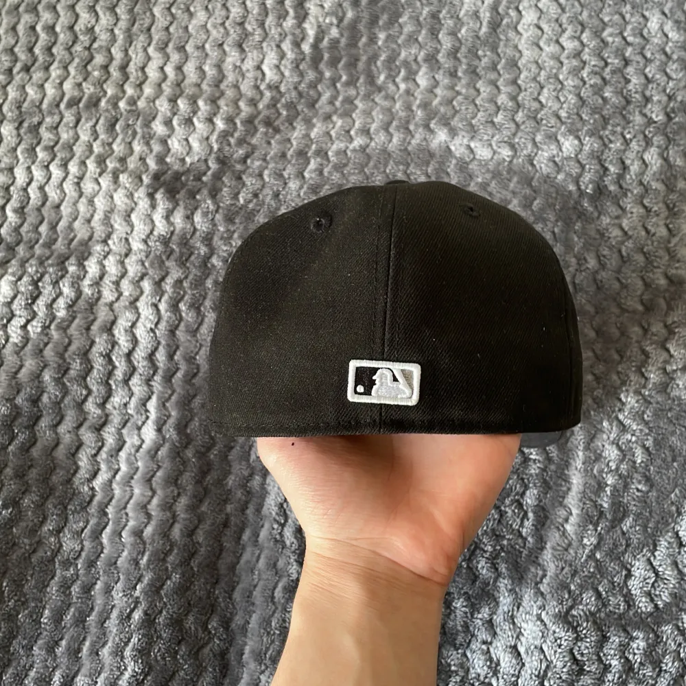 Snygg svart keps från New Era med broderad logga på framsidan. Perfekt för att komplettera din streetwear-look. Kepsen har en klassisk design med en rak skärm och är tillverkad i bomull.. Asusteet.