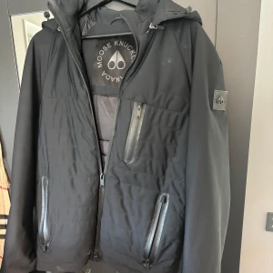 Moose Knuckles hybrid jacka  - Moose Knuckles jacka köpt på johnells i vintras men knappast använd där av skicket på jackan. Lite små fläckar som syns på bilderna men det går bort efter en lätt liten tvätt. Tveka inte på att höra av dig om du har några frågor, priset är inte hugget i sten vid snabb affär🤝 finns äkthets bevis!