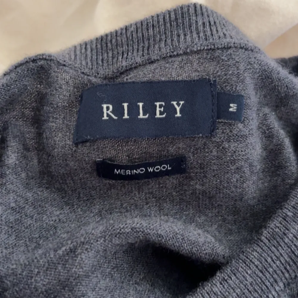 Säljer en stilren grå tröja från Riley i mjuk merinoull. Perfekt för kyligare dagar med sin långärmade design och bekväma passform. Ett måste i garderoben för den som gillar klassisk stil.. Neuletakit & Villapaidat.