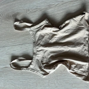 Beige linnetopp från Divided - Säljer en stilren beige linnetopp från Divided. Toppen har smala axelband och är perfekt för varma dagar. Enkel och snygg design som passar till det mesta. Perfekt för sommaren!