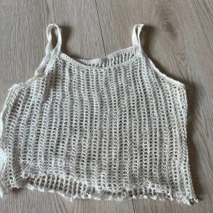 Vit stickad linnetopp cover upp  - Säljer en vit cover upp stickad linnetopp med ett luftigt och öppet mönster. Toppen har smala axelband och en avslappnad passform, perfekt för varma sommardagar. Passar bra över en bikini eller som en del av en lager-på-lager-look.🩷