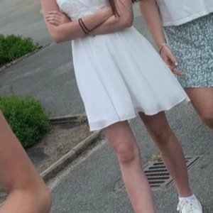 Vit miniklänning  - Säljer en elegant vit klänning från Bubbleroom med spetsdetaljer och v-ringning. Klänningen har smala axelband och en flödande kjol. Perfekt till studenten eller skolavslutningen. Har fina spetsdetaljer övertill. Endast använd en gång på skolavslutningen i åttonde klass. Säljes tyvärr då den är för liten, men den är verkligen superfin. Inga defekter. 💕