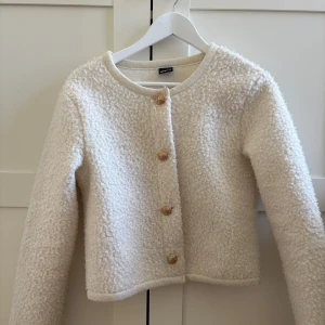 Vit teddyjacka med knappar - Säljer denna jättefina mysiga, vita teddyjacka med rund hals och dekorativa knappar framtill. Perfekt nu i vår när du vill ha något både stilrent och bekvämt. Köptes på Gina Tricot för ett år sen men inte använd så mycket och alltså i bra skick. Tveka inte att skriva om ni har några frågor eller önskar mer bilder.💞💞