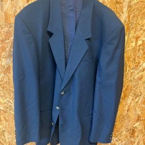 Mörkblå kavaj - Snygg mörkblå kavaj med klassisk design och knappar framtill. Perfekt för en stilren look.