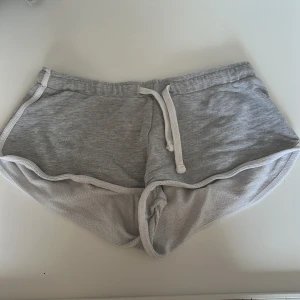 Grå shorts från - Säljer ett par grå shorts i storlek XXS. De är tillverkade i ett mjukt material med snörning i midjan för justerbar passform. Perfekta för en avslappnad stil.