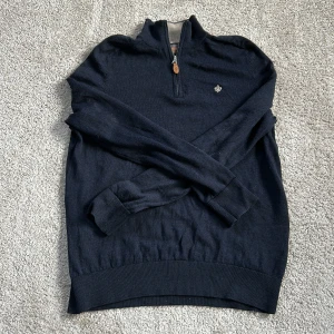 Mörkblå tröja med dragkedja från Morris - Säljer en stilren mörkblå tröja från Morris med halv dragkedja och broderad logga på bröstet. Tröjan har långa ärmar och ribbade muddar vid ärmslut och nederkant. Perfekt för en avslappnad men snygg look. Har varit ett litet hål i tröjan men det är igensytt. 100% merino ull. I storlek S men den är ganska liten i storleken. Priset är ej hugget i sten.