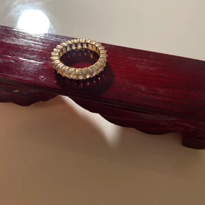 Guldfärgad ring med stenar - Elegant guldfärgad ring med klara stenar runt om. Perfekt för att ge en glittrig touch till din stil. Passar bra till både vardag och festliga tillfällen. Jag vet tyvärr inte storleken på den men den är lite stor på mig iallafall. Priset går att diskutera💞