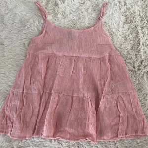 Rosa somrig topp! - Söt rosa top från Divided med smala axelband. Perfekt för varma dagar med sin lätta och sköna design. Klänningen har en avslappnad passform och är gjord i ett mjukt material. Aldieg använd och super skick 💕pris kan diskuteras skriv också för bilder på💕passar XXS/XS