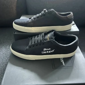 Svarta sneakers från Saint Laurent - Snygga svarta sneakers från Saint Laurent med vit sula och klassisk snörning. Skorna har en stilren design med Saint Laurent-logga på sidan och insidan. Perfekta för en trendig och avslappnad look.