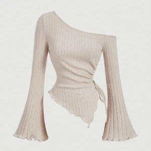 Beige ribbad oneshoulder topp - Snygg beige oneshoulder topp med ribbad design och asymmetrisk nederkant. Toppen har långa ärmar och en figurnära passform som framhäver silhuetten. Perfekt för en trendig look!