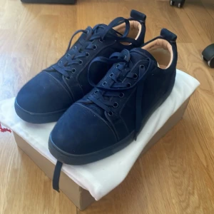 Mörkblå Loubs - Snygga mörkblå sneakers med en ikonisk röd sula. Skorna har snörning och en rund tå, vilket ger en klassisk look. Perfekta för en stilren vardagsstil.