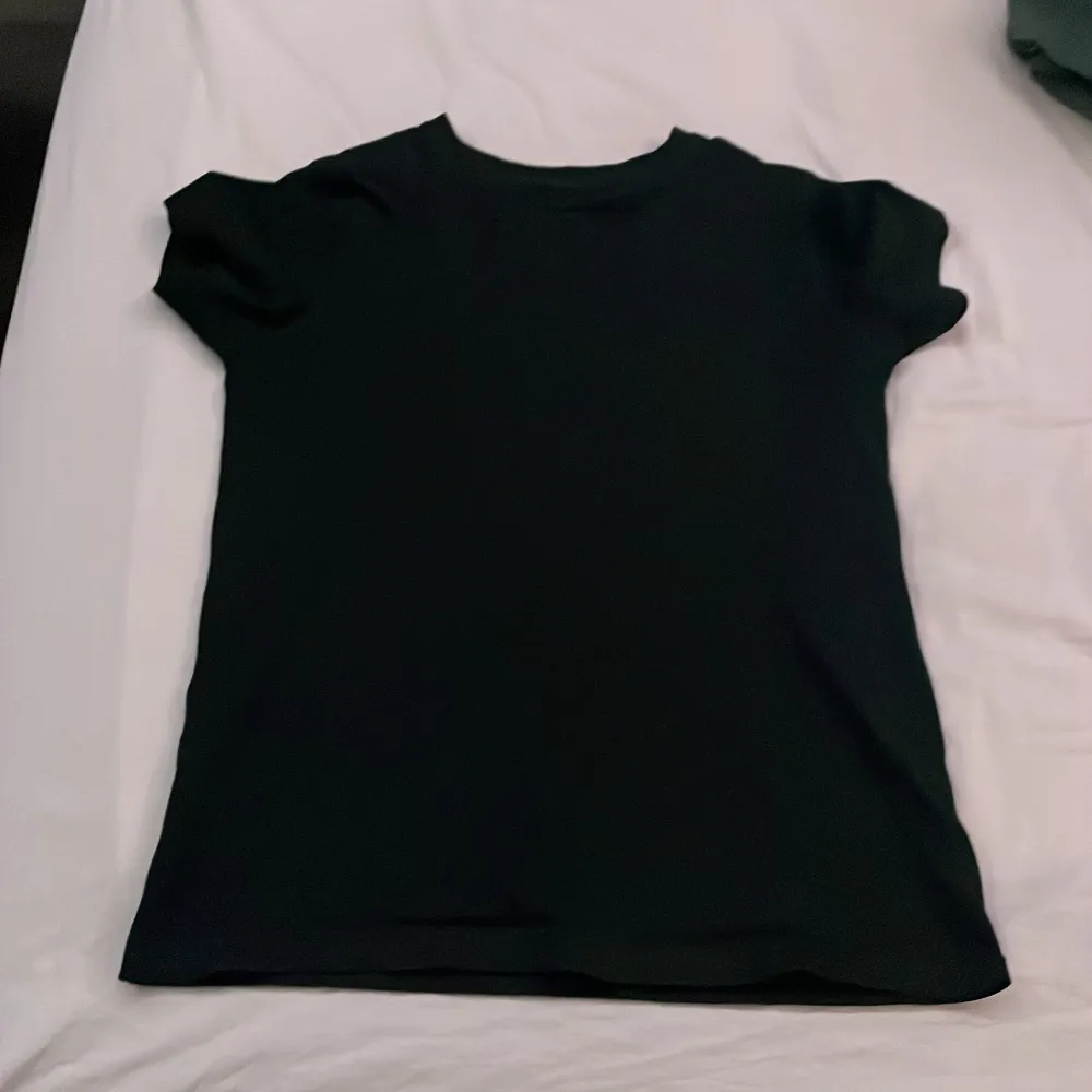 Säljer en klassisk svart t-shirt från Newbody i storlek 140/150. Den är tillverkad av 100% bomull och har en enkel design med korta ärmar. Perfekt för en stilren look.. T-paidat.