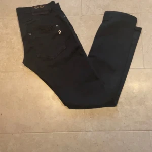 dondup jeans - Snygga svarta jeansbyxor med normal passform. Byxorna har en klassisk design med fem fickor och knappgylf. Perfekta för en stilren look.