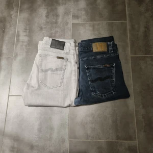 Två par nudie  jeans i olika färger - Säljer två par nudie jeans, ett par i ljusgrått och ett i svart. Skick 5/10 dem är lite slitna där bak och där fram. Därför kan priset diskuteras. Storlek på gråa, w29 L32 och de svarta, W28, L30. Båda moderera är slim/skinny 