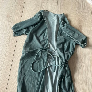 Grön transparent cover upp med knytband - Snygg grön transparent cover upp med knytband i midjan. Perfekt för lager-på-lager-stil. Klänningen har trekvartsärmar och är tillverkad i ett lätt och luftigt material.🩷