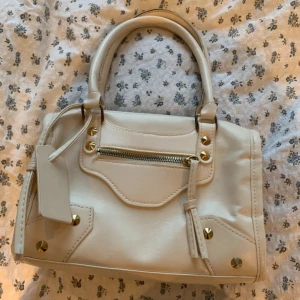 Vit city bag - Snygg vit handväska i skinnimitation med  nitar och dragkedja framtill. City väska i fint skick