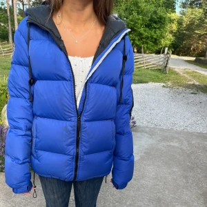 Blå dunjacka från D brand  - Snygg blå dunjacka från D brand med svarta detaljer Flera fickor med dragkedja på in sida och utsida. Den är använd en vinter men väldigt fräsch.